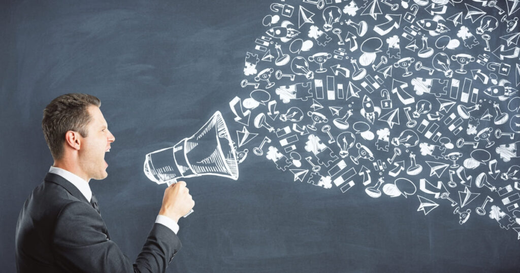 Hombre comunicando con un megáfono conceptos de marca dibujados en pizarra