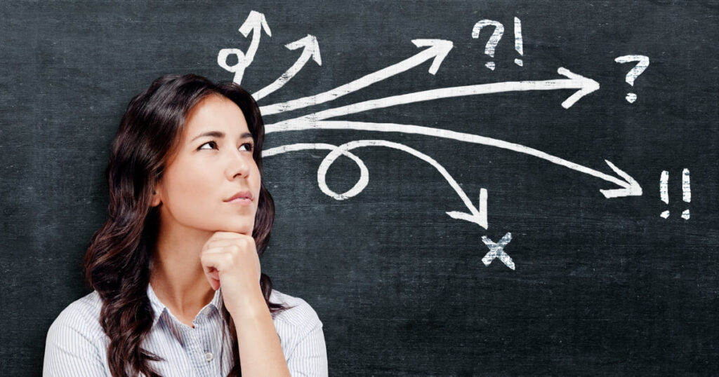 Mujer reflexionando frente a una pizarra con flechas, representando decisiones estratégicas bajo presión.