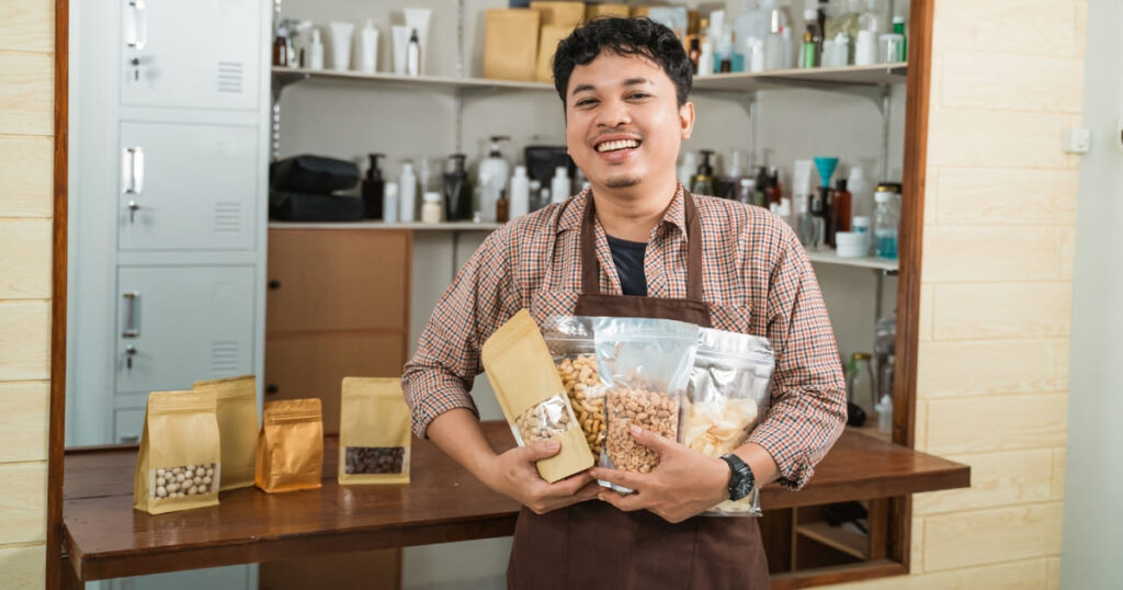 Emprendedor feliz sosteniendo productos en empaque propio, símbolo de una marca sólida que vende sin necesidad de descuentos.